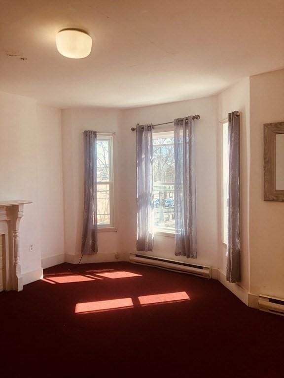 carpeted empty room with baseboard heating and plenty of natural light