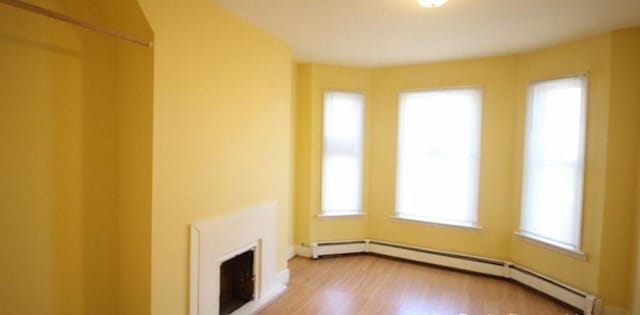 unfurnished living room with hardwood / wood-style floors and baseboard heating