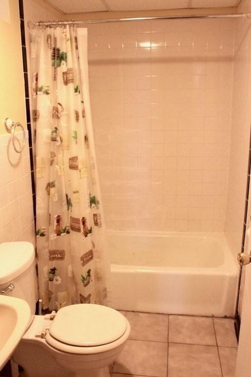 bathroom with toilet, tile patterned floors, and shower / bath combo with shower curtain