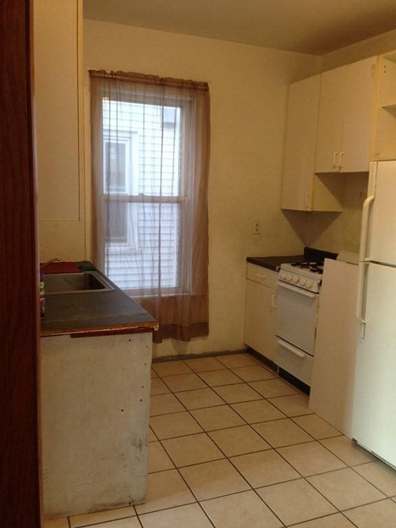 kitchen with white cabinetry, white appliances, sink, and light tile patterned floors