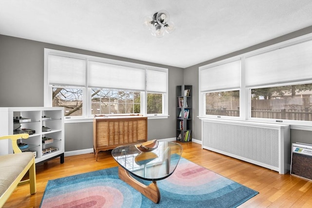 living area featuring radiator, wood finished floors, and baseboards