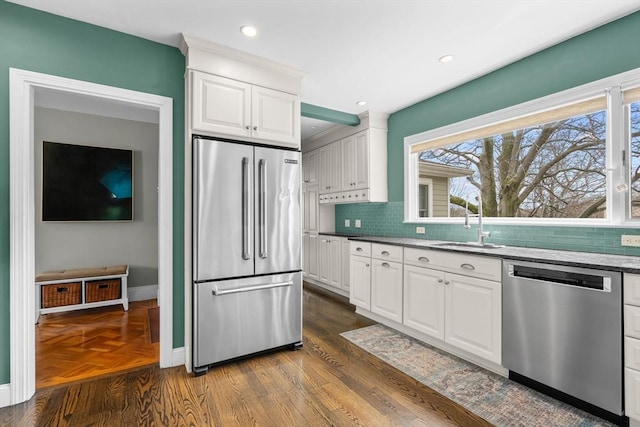 kitchen with appliances with stainless steel finishes, backsplash, baseboards, and a sink