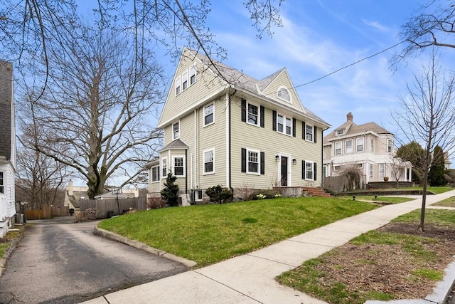 traditional style home featuring fence and a front lawn