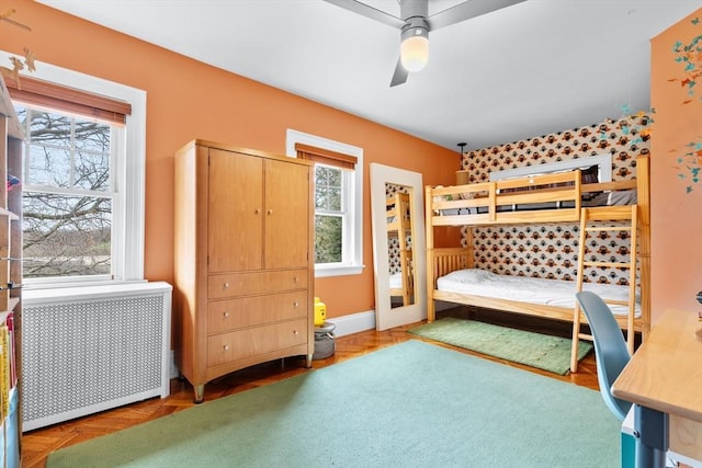 bedroom with radiator heating unit, a ceiling fan, and multiple windows
