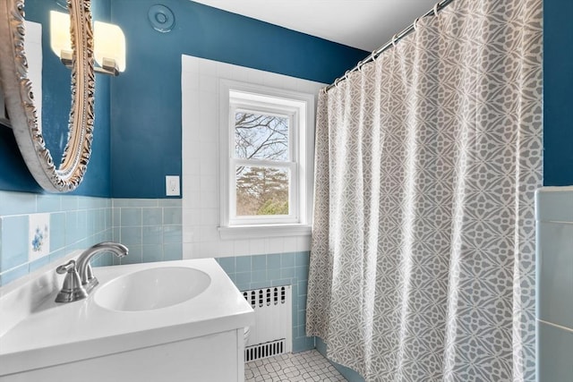 bathroom featuring tile patterned flooring, a shower with curtain, tile walls, radiator heating unit, and vanity