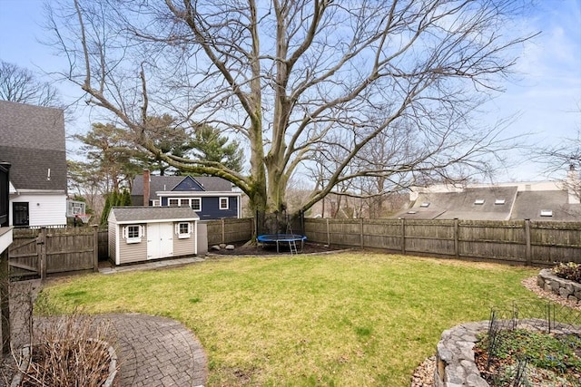 view of yard featuring an outbuilding, a trampoline, a storage unit, and a fenced backyard