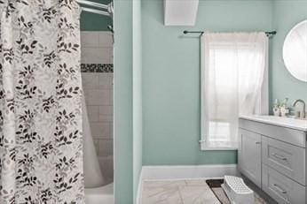 bathroom featuring shower / bath combo with shower curtain, vanity, and baseboards
