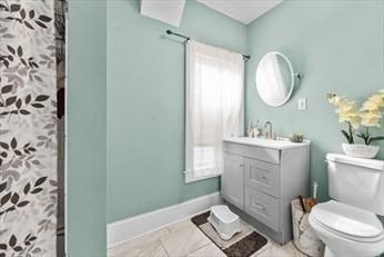 full bath with curtained shower, baseboards, vanity, and toilet