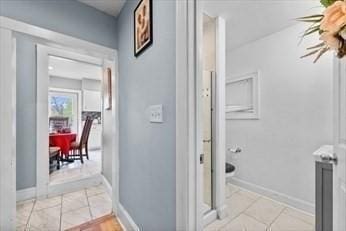 corridor with light tile patterned floors and baseboards
