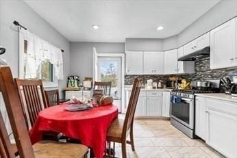 kitchen featuring stainless steel range with gas stovetop, under cabinet range hood, and white cabinetry