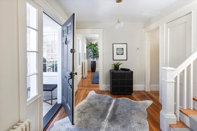 doorway to outside featuring radiator, baseboards, stairway, and wood finished floors