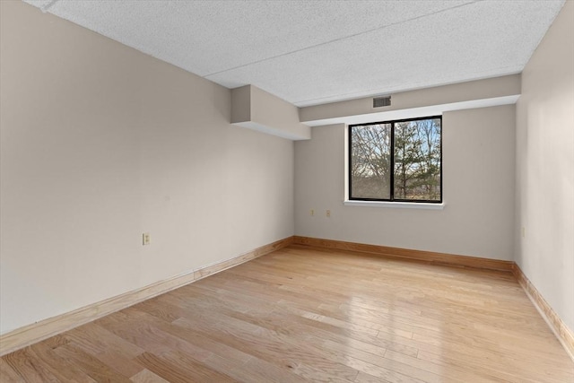 unfurnished room with a textured ceiling and light wood-type flooring