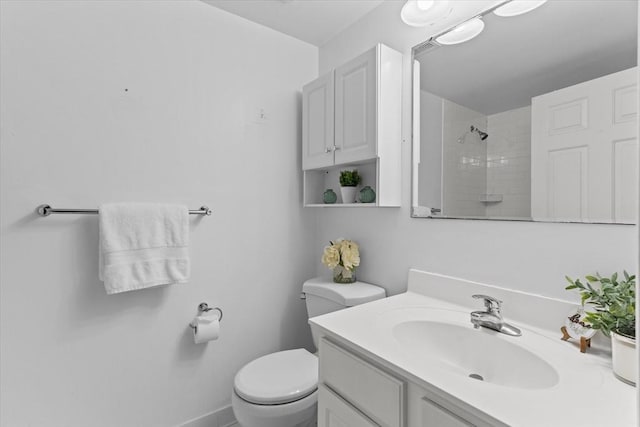 bathroom featuring tiled shower, vanity, and toilet