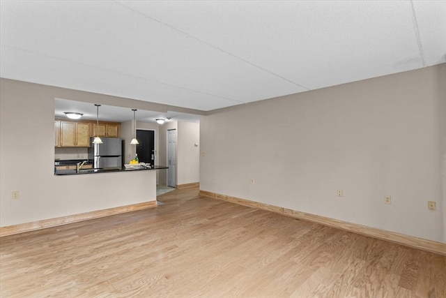 unfurnished living room featuring sink and light hardwood / wood-style floors