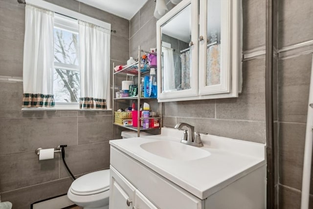 bathroom with tile walls, vanity, toilet, and baseboard heating