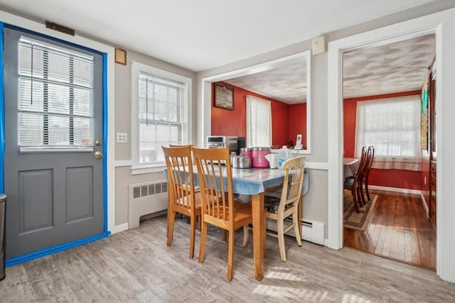 dining area with light hardwood / wood-style flooring and radiator heating unit