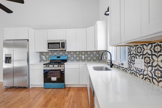 kitchen with light countertops, stainless steel appliances, decorative backsplash, and a sink