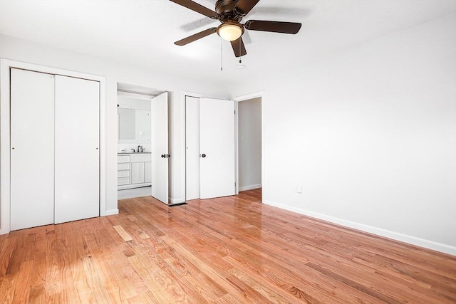 unfurnished bedroom with a sink, multiple closets, baseboards, and light wood-style flooring