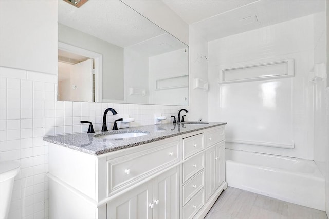 bathroom with a sink, tile walls, and double vanity