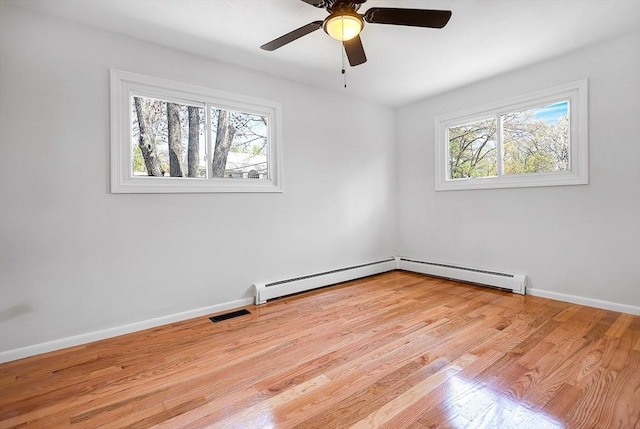 spare room with a healthy amount of sunlight, light wood-style floors, and baseboard heating