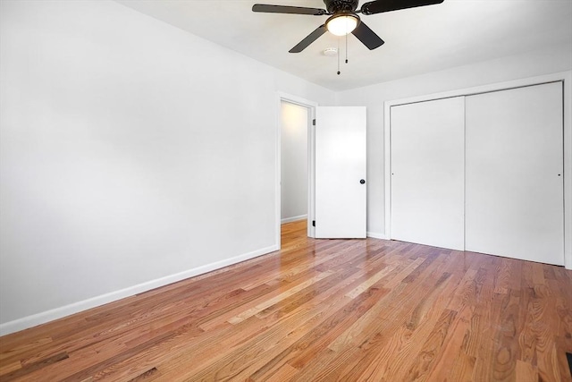 unfurnished bedroom with baseboards, ceiling fan, wood finished floors, and a closet