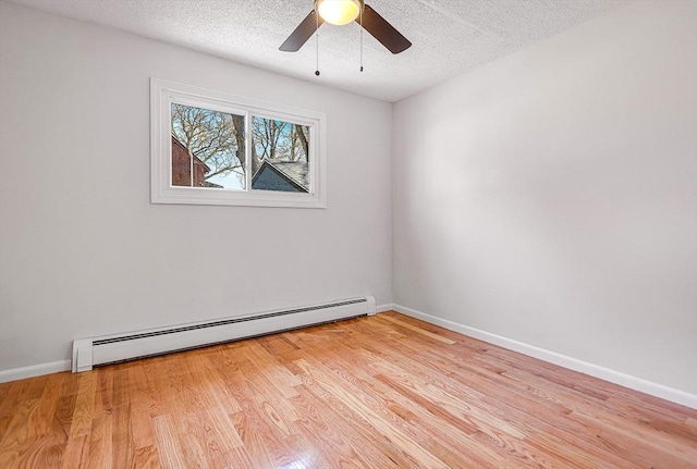 spare room with wood finished floors, baseboards, ceiling fan, a textured ceiling, and a baseboard heating unit