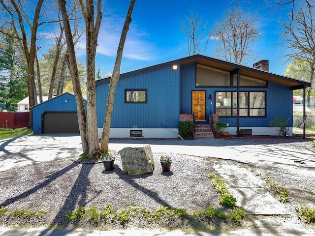 mid-century inspired home featuring a garage, fence, an outbuilding, and a chimney