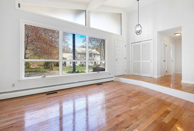 interior space with beam ceiling, high vaulted ceiling, baseboards, wood finished floors, and a baseboard radiator