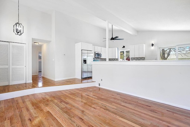 unfurnished living room with high vaulted ceiling, beamed ceiling, a ceiling fan, and a wealth of natural light
