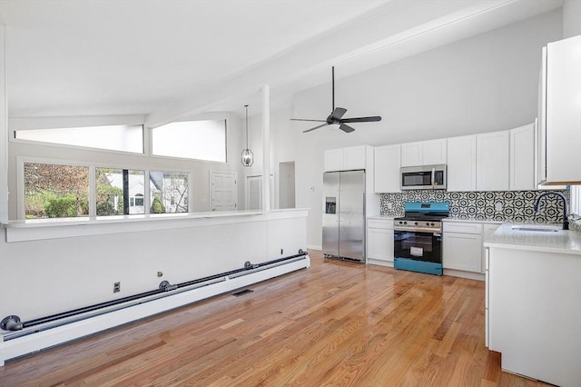 kitchen with light countertops, a baseboard heating unit, a sink, backsplash, and stainless steel appliances