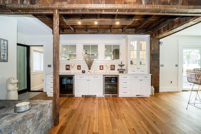 bar with a dry bar, light wood-style flooring, wine cooler, and beamed ceiling