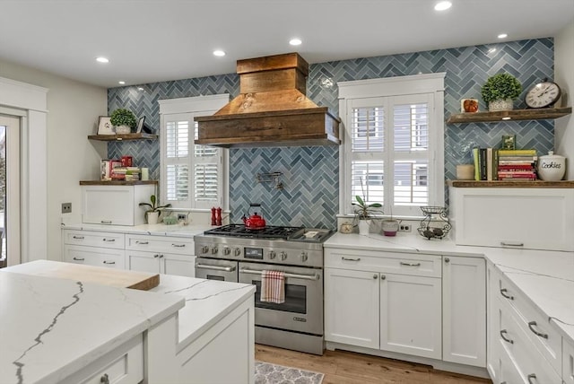 kitchen with recessed lighting, white cabinetry, high end range, open shelves, and custom range hood