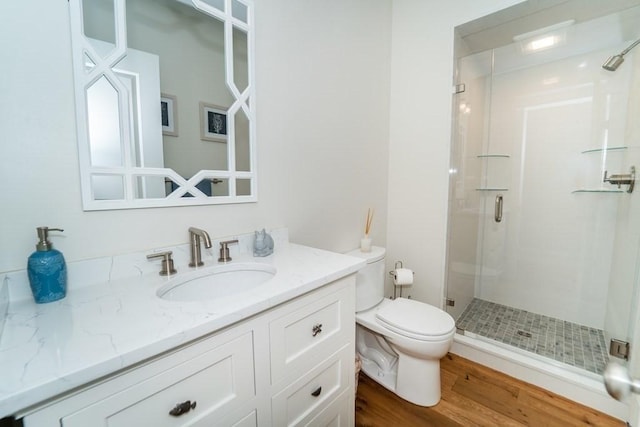 full bath with toilet, a stall shower, wood finished floors, and vanity