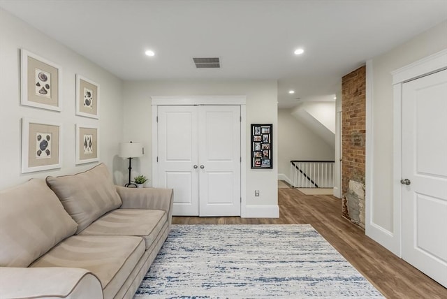 living room with recessed lighting, visible vents, baseboards, and wood finished floors