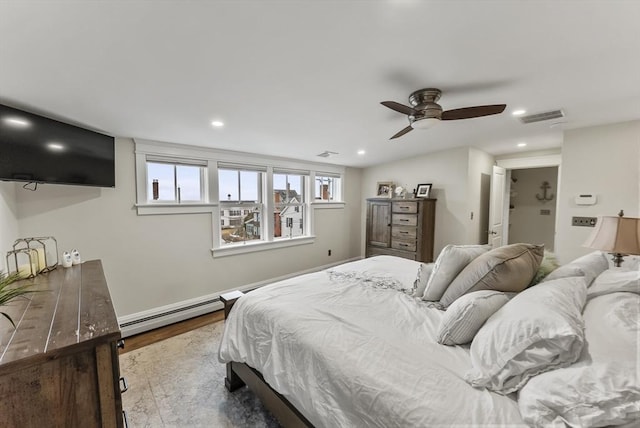 bedroom with a baseboard heating unit, wood finished floors, visible vents, and recessed lighting