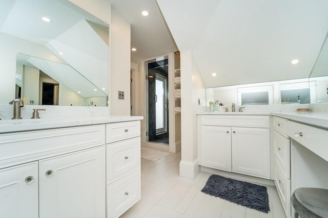 bathroom featuring recessed lighting, two vanities, a sink, vaulted ceiling, and a stall shower