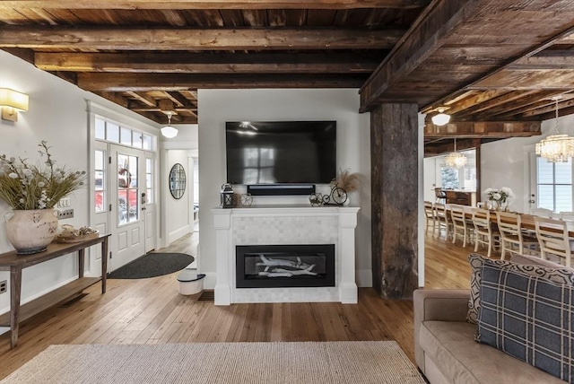 living room featuring wooden ceiling, hardwood / wood-style flooring, beamed ceiling, and a glass covered fireplace