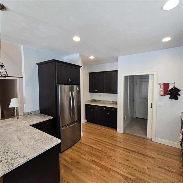 51 Alexandras Way, Brockton, MA 02301 - kitchen featuring stainless steel refrigerator, light wood-style floors, dark cabinets, light stone counters, and baseboards