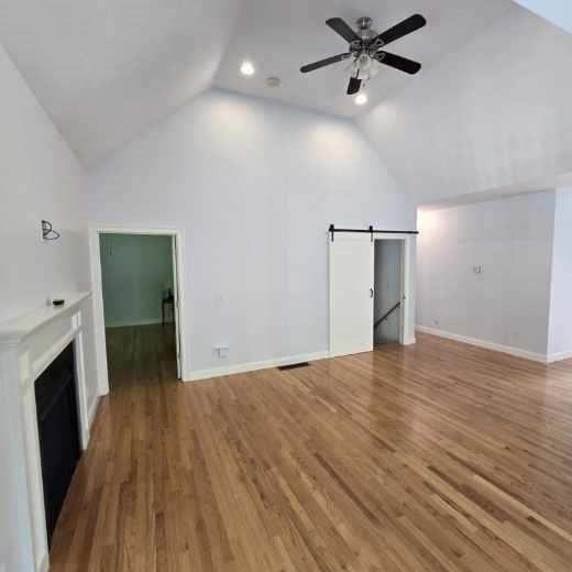 51 Alexandras Way, Brockton, MA 02301 - unfurnished living room featuring vaulted ceiling, a barn door, a ceiling fan, wood finished floors, and a fireplace