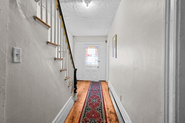 entryway featuring a textured ceiling, baseboard heating, and light hardwood / wood-style flooring