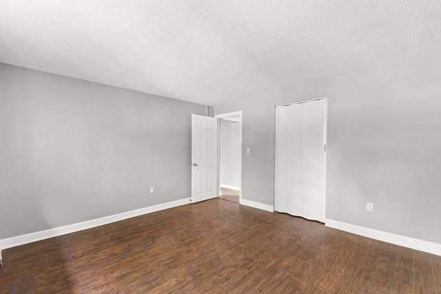 unfurnished room with dark wood-type flooring and a textured ceiling