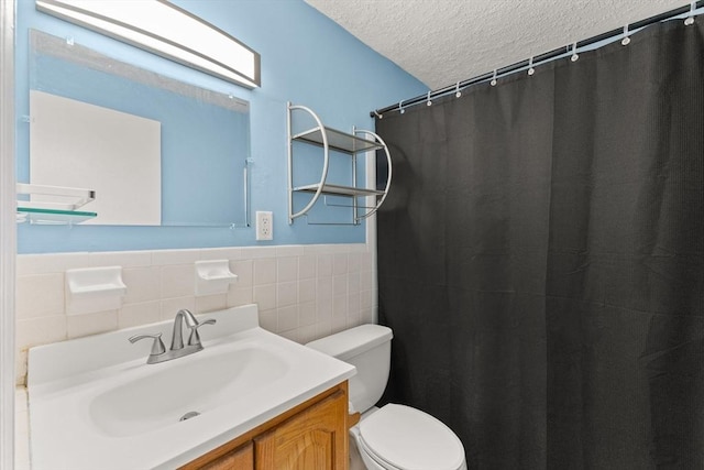 bathroom with vanity, tile walls, toilet, and a textured ceiling