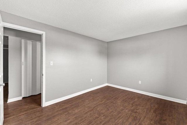 spare room with dark wood-type flooring and a textured ceiling