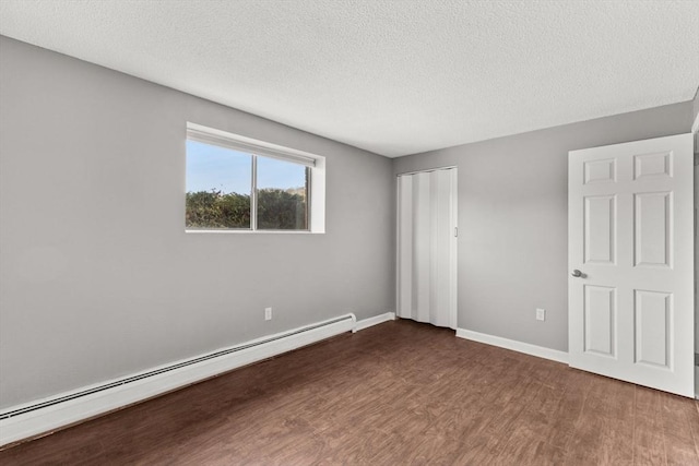 unfurnished bedroom with a baseboard heating unit, a closet, dark hardwood / wood-style floors, and a textured ceiling