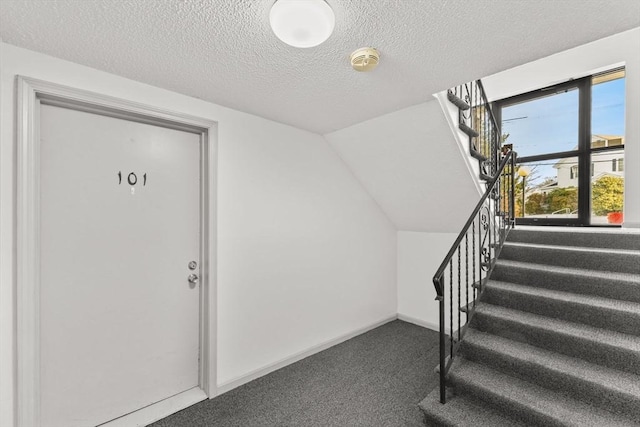 stairs featuring lofted ceiling, carpet flooring, and a textured ceiling