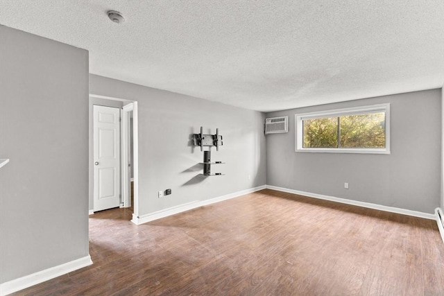 spare room with dark hardwood / wood-style floors, a textured ceiling, and an AC wall unit