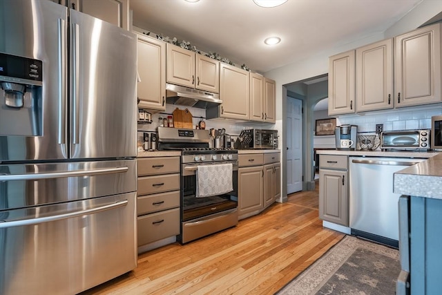 98 Moss St, New Bedford, MA 02744 - kitchen featuring stainless steel appliances, under cabinet range hood, light wood finished floors, backsplash, and light countertops