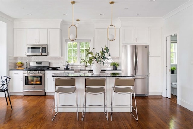 14 S Waverly St Unit 14, Boston, MA 02135 - kitchen featuring appliances with stainless steel finishes, a center island, a kitchen breakfast bar, decorative backsplash, and white cabinetry