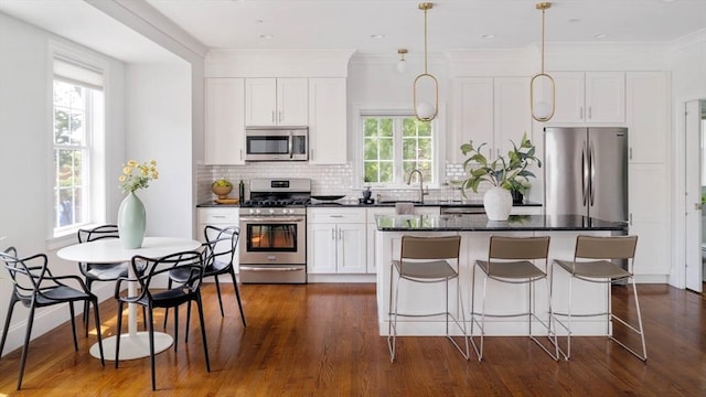 14 S Waverly St Unit 14, Boston, MA 02135 - kitchen with appliances with stainless steel finishes, a center island, white cabinetry, backsplash, and dark wood-style flooring