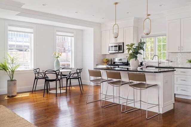 14 S Waverly St Unit 14, Boston, MA 02135 - kitchen featuring stainless steel appliances, backsplash, dark wood-type flooring, a kitchen island, and white cabinetry